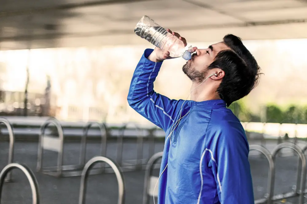 Man resting and drinking water after run